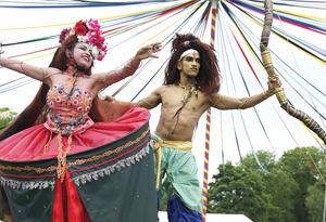 Woman and man in festival tribe clothes doing a dance in a tent